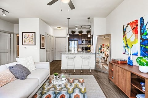 A living room with a white couch and a colorful rug.